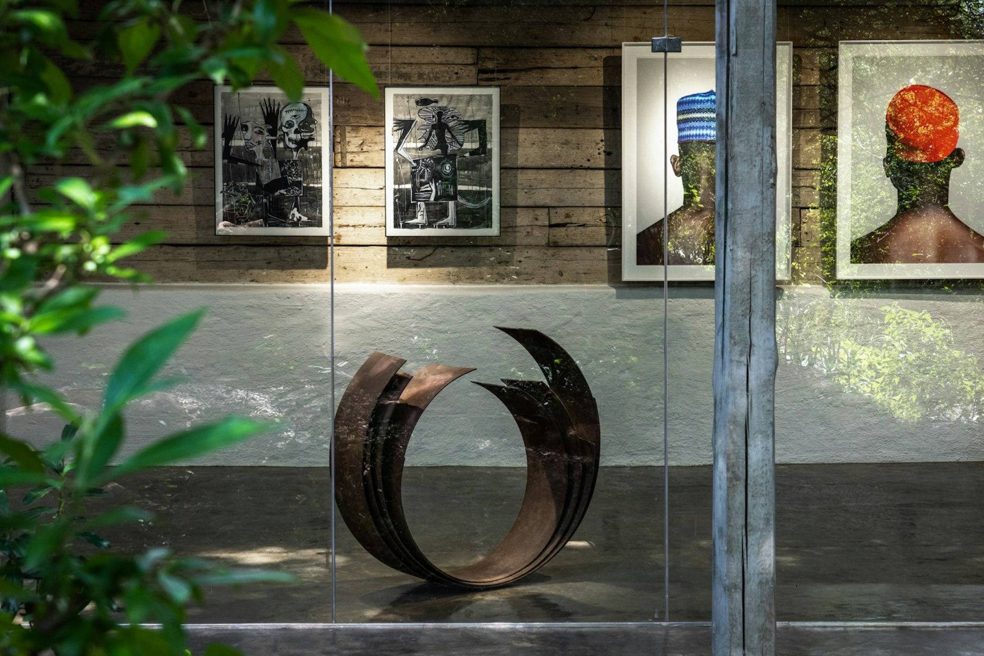 A round metal sculpture with art prints on the wall in Singita Art Gallery